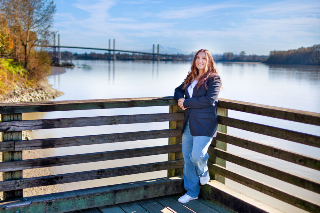 A photo of Julie standing on a deck overlooking a beautiful landscape of a bridge