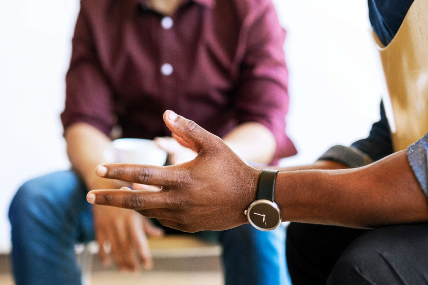 Image of two people sitting and talking in a group setting