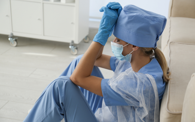 Doctor sitting on floor with hands on forehead